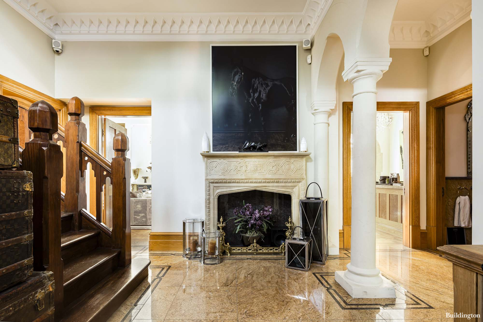 Ground-floor entrance hall in The Vicarage features an original limestone fireplace bearing the date AD1886 and granite flooring, off the hall is the Gothic style staircase leading to the upper floors, with original stained glass windows on the landings cascading the stairwell and hall